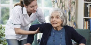Caregiver Assisisting Old Woman with Alzheimers in Standing